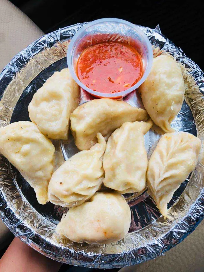 Steamed and fried street momos served with spicy red chutney in Delhi